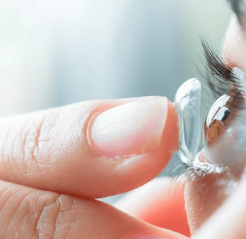 hybrid contact on finger tip being placed on the eyeball