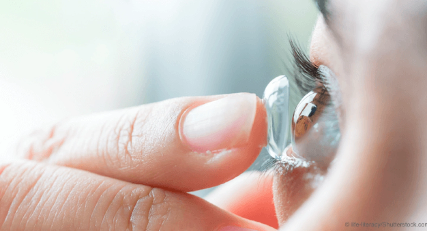 hybrid contact on finger tip being placed on the eyeball